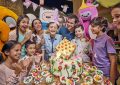 Birthday party celebration at IMG Worlds of Adventure with kids, parents, a themed cake, and cartoon character