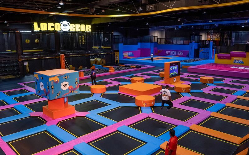 Indoor trampoline park at Loco Bear Dubai with vibrant pink, blue, and orange trampolines